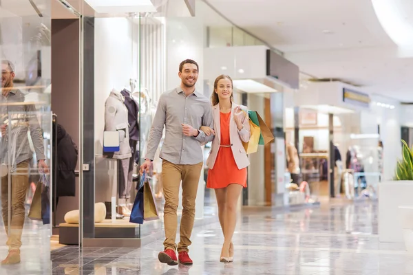 Glückliches junges Paar mit Einkaufstüten in Einkaufszentrum — Stockfoto