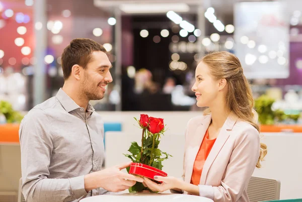 Glückliches Paar mit Geschenk und Blumen in Einkaufszentrum — Stockfoto