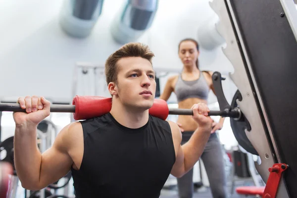 Man and woman with barbell flexing muscles in gym — Stock Photo, Image