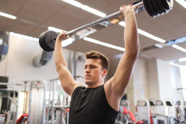 Ung man böjande muskler med skivstång i gymmet — Stockfoto