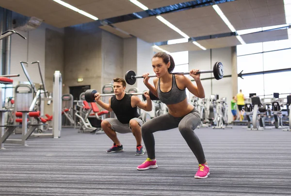 Jovem homem e mulher formação com barbell no ginásio — Fotografia de Stock