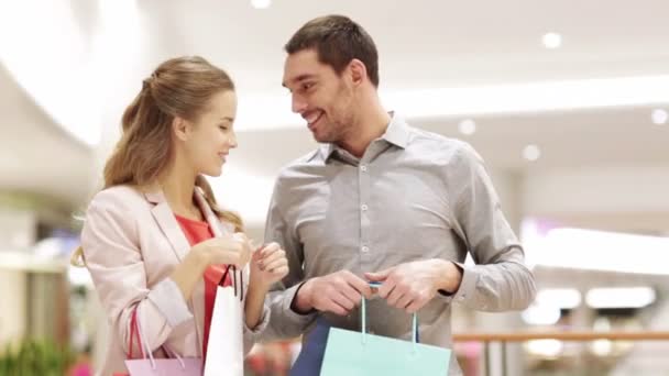 Feliz pareja joven con bolsas de compras en el centro comercial — Vídeos de Stock