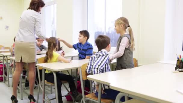 Professor dando canetas para crianças da escola em sala de aula — Vídeo de Stock