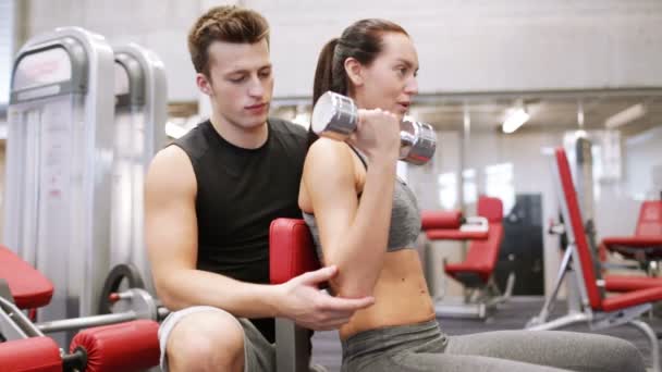 Pareja joven con músculos de flexión de mancuerna en el gimnasio — Vídeos de Stock