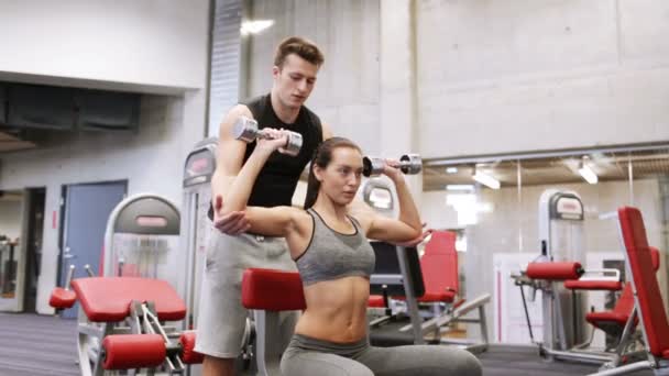 Jovem casal com halteres flexionando músculos no ginásio — Vídeo de Stock