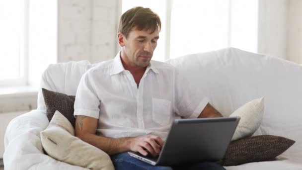 Hombre trabajando con el ordenador portátil en casa — Vídeos de Stock