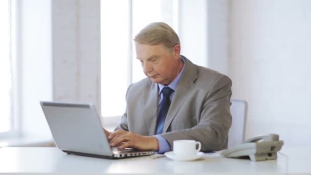 Oude man met laptopcomputer drinken koffie — Stockvideo