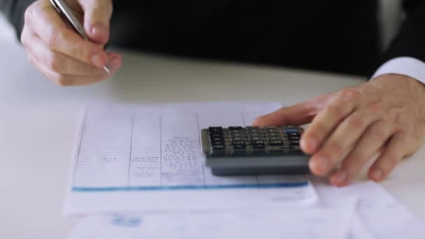 Hombre con calculadora llenando un formulario — Vídeo de stock