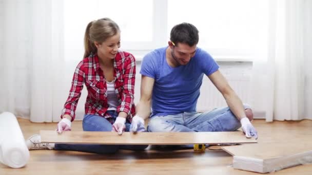 Pareja sonriente midiendo pisos de madera — Vídeos de Stock