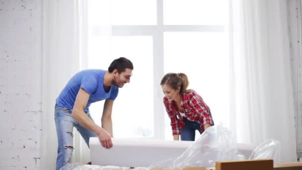 Pareja sonriente abriendo gran caja de cartón con sofá — Vídeo de stock