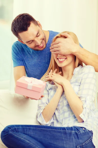 Un homme souriant surprend sa petite amie avec un cadeau — Photo