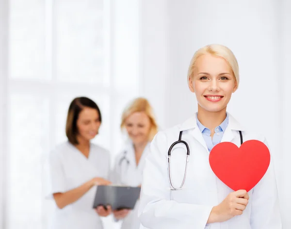 Médica sorridente com coração e estetoscópio — Fotografia de Stock