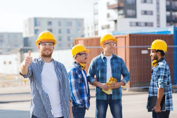 Groep van lachende bouwers in hardhats in openlucht — Stockfoto