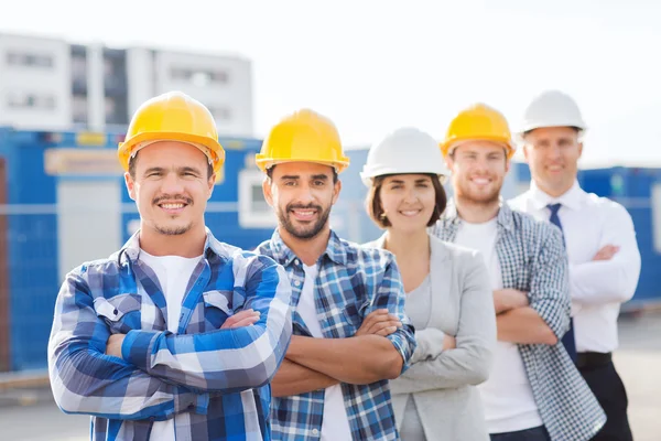 Grupo de construtores sorridentes em hardhats ao ar livre — Fotografia de Stock