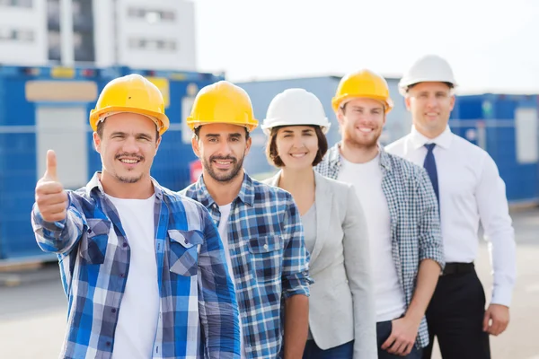 Grupp av leende byggare i hardhats utomhus — Stockfoto