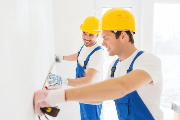 Smiling builders with measuring tape indoors — Stock Photo, Image