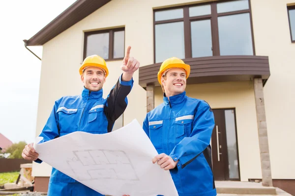 Smiling builders with blueprint pointing finger — Stock Photo, Image