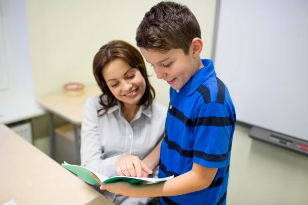 Skolan pojke med anteckningsboken och lärare i klassrummet — Stockfoto