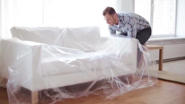 Мужчина сложит новый диван дома — стоковое видео