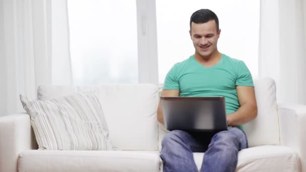 Улыбающийся человек, работающий с ноутбуком дома — стоковое видео