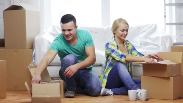 Pareja sonriente desempacando cajas con utensilios de cocina — Vídeos de Stock