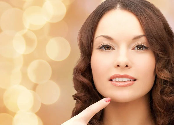 Beautiful young woman pointing finger to her chin — Stock Photo, Image