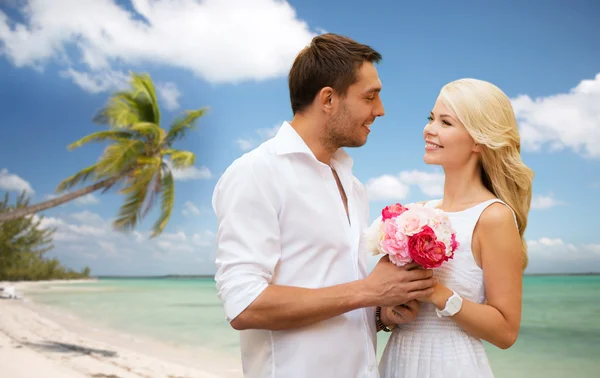 ビーチの背景の上の花で幸せなカップル — ストック写真