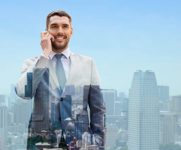 Smiling businessman with smartphone in city — Stock Photo, Image