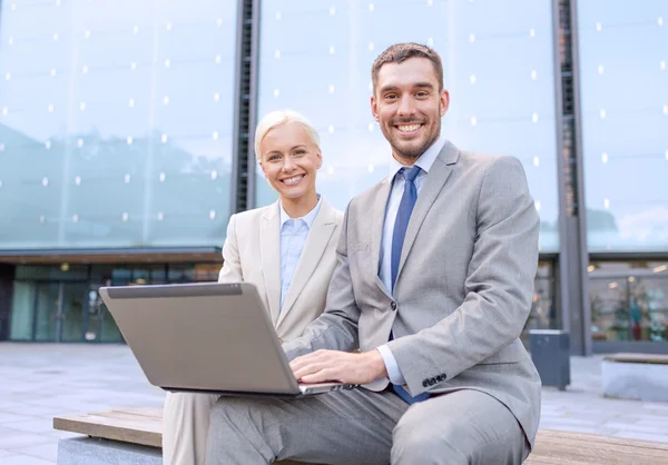 Sonrientes empresarios con portátil al aire libre — Foto de Stock