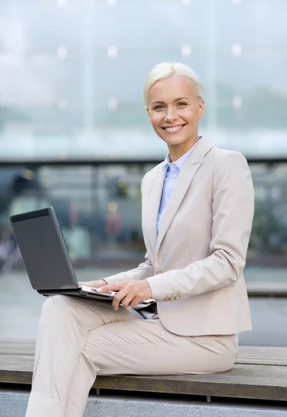 Uśmiechnięta kobieta pracuje z laptopa na zewnątrz — Zdjęcie stockowe