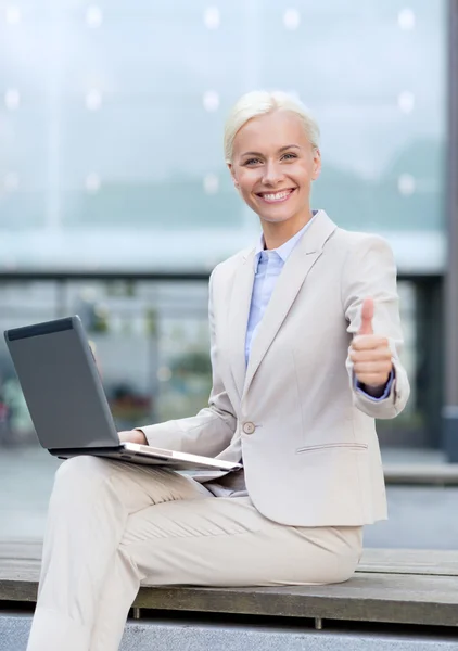 Улыбающаяся деловая женщина, работающая с ноутбуком на открытом воздухе — стоковое фото