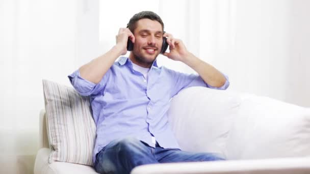 Usmívající se mladý muž se sluchátky doma — Stock video
