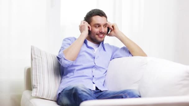 Jeune homme souriant avec écouteurs à la maison — Video