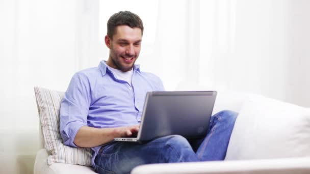 Усміхнений чоловік працює з ноутбуком вдома — стокове відео
