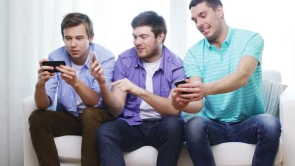 Amigos sonrientes con teléfonos inteligentes en casa — Vídeos de Stock