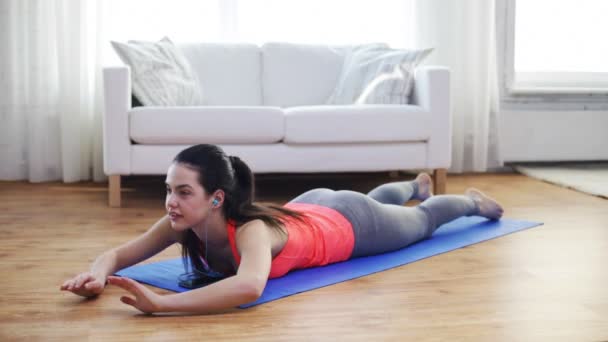 Mujer sonriente con smartphone haciendo ejercicio en casa — Vídeos de Stock