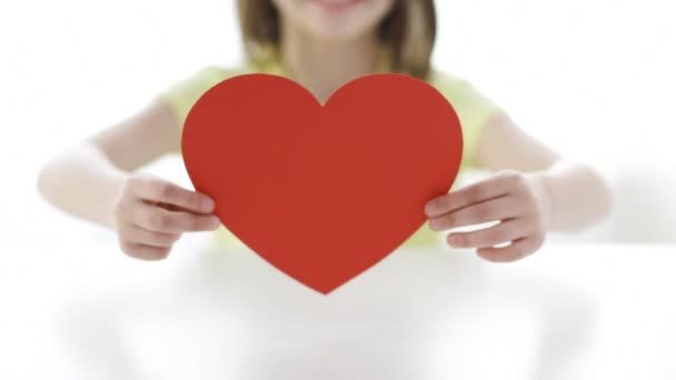 Close-up of smiling girl with red heart at home — Stock Video