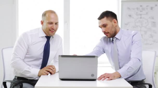 Dos hombres de negocios sonrientes con portátil en la oficina — Vídeo de stock