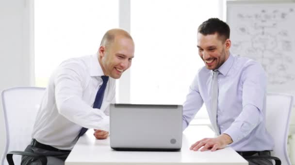 Δύο χαμογελαστά επιχειρηματίες με φορητό υπολογιστή στο γραφείο — Αρχείο Βίντεο