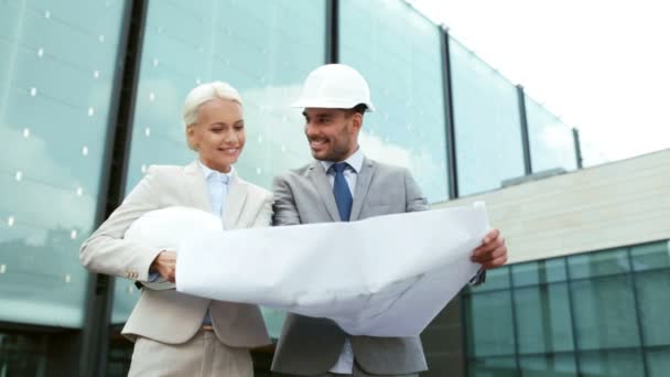 Smiling businessmen with blueprint and helmets — Stock Video