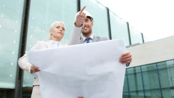 Hombres de negocios sonrientes con planos y cascos — Vídeos de Stock