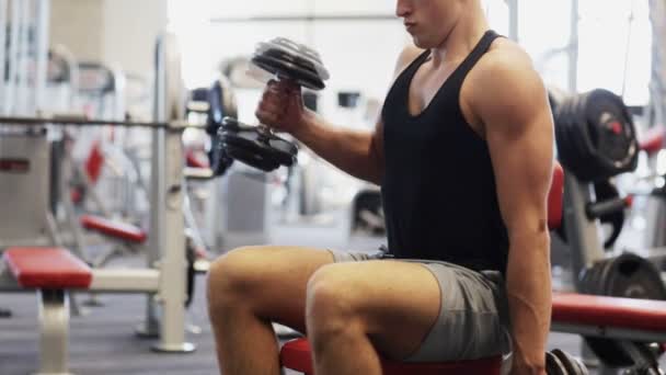 Jeune homme avec haltères dans la salle de gym — Video