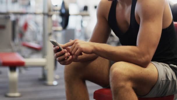 Jeune homme avec smartphone dans la salle de gym — Video