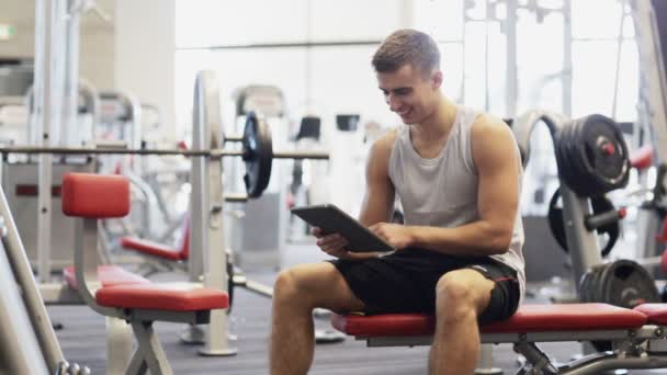 Uśmiechający się młodego człowieka z komputerem pc tabletka w siłowni — Wideo stockowe