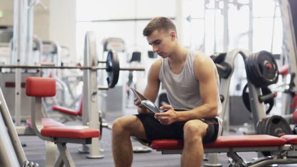 Young man with tablet pc computer in gym — Stock Video