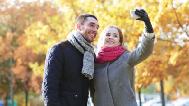 Pareja sonriente con teléfono inteligente en el parque de otoño — Vídeos de Stock