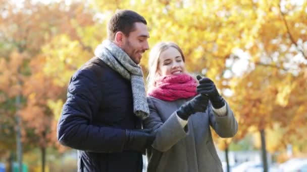 Pareja sonriente con teléfono inteligente en el parque de otoño — Vídeo de stock