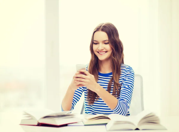 Lachende student meisje met smartphone en boeken — Stockfoto