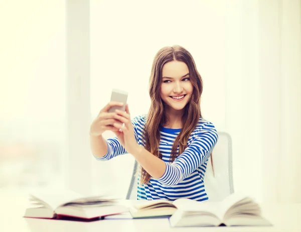 Chica estudiante sonriente con teléfono inteligente y libros — Foto de Stock