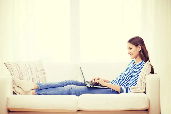 Sonriente adolescente con ordenador portátil en casa —  Fotos de Stock